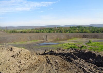 Landscape view of long, flat dirt pad with steep, angular slope into pit