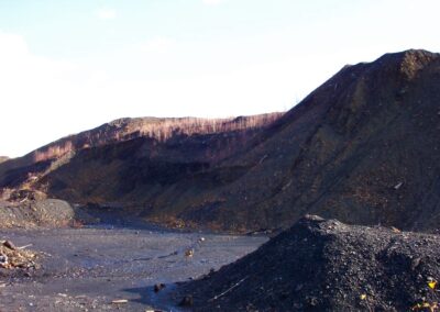 Large, barren piles of mining waste tower over a metal cushioned chair