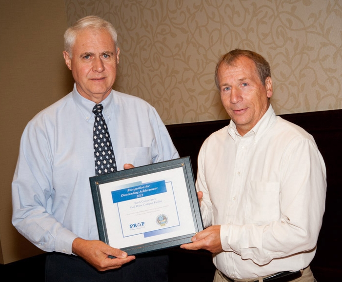 Man (John Renfer) in tie on left holds award plaque with another man on right
