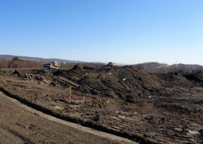 Two bulldozers push dirt and rock along steep slope
