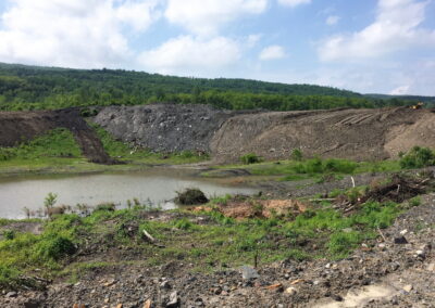 Small bulldozer on right side of large unreclaimed slope; water has ponded at foot.