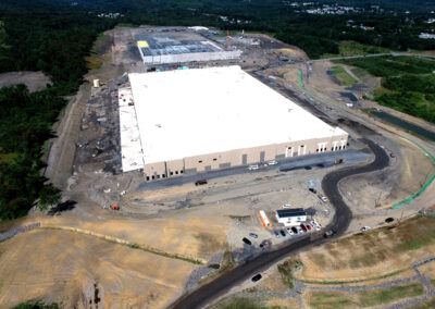 Aerial view of large construction site with two warehouse buildings; one in foreground is complete, one in background is underway