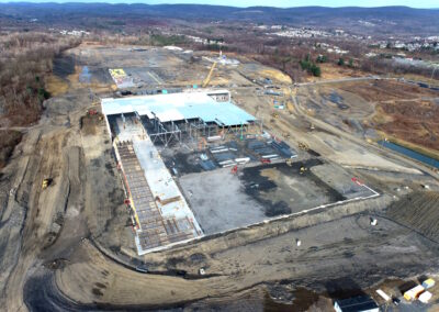 Aerial view of large construction site with one warehouse building in foreground being constructed