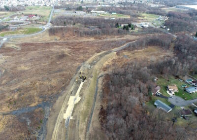 Aerial view of new, wide channel with large, seeded swales. A small neighborhood is to the right.