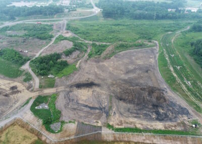 Large area of mine-scarred land with dirt being moved by heavy equipment.