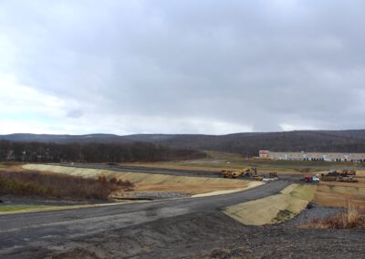 Unimproved road leading to flat construction site with heavy equipment on it.