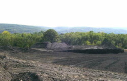 Landscape view of dirt.mine spoil area partially flattened. Ground shows tracks from construction vehicles.