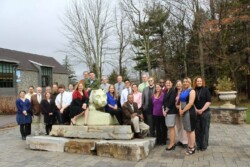 Group of 30+ adults surround and sit on statue of Penn State Nittany lion